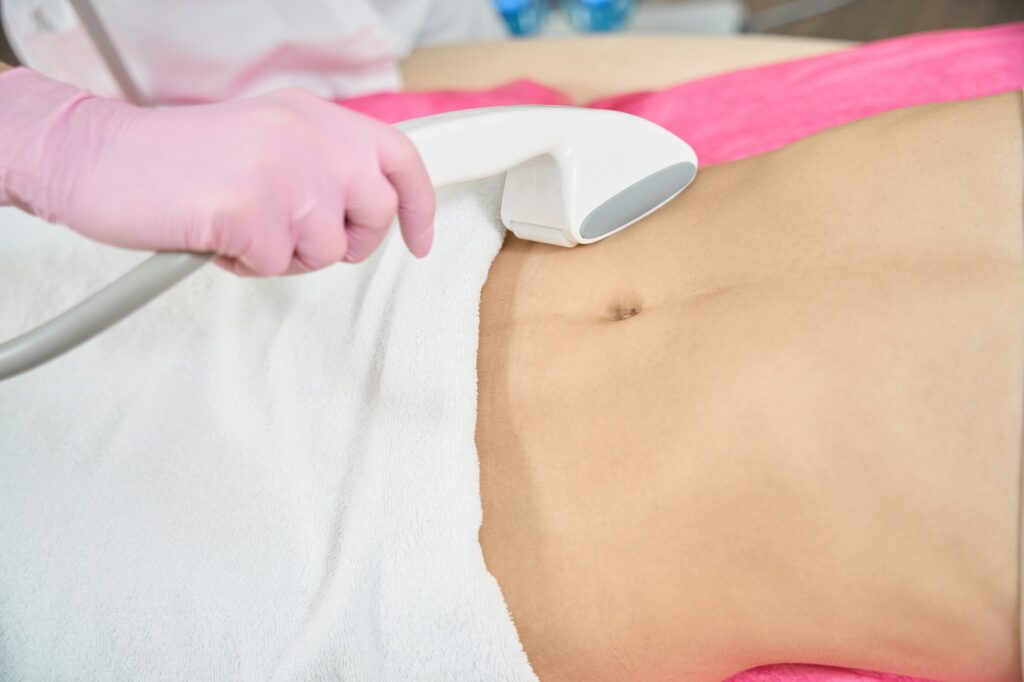 Aesthetic medical practitioner performing body contouring treatment on patient