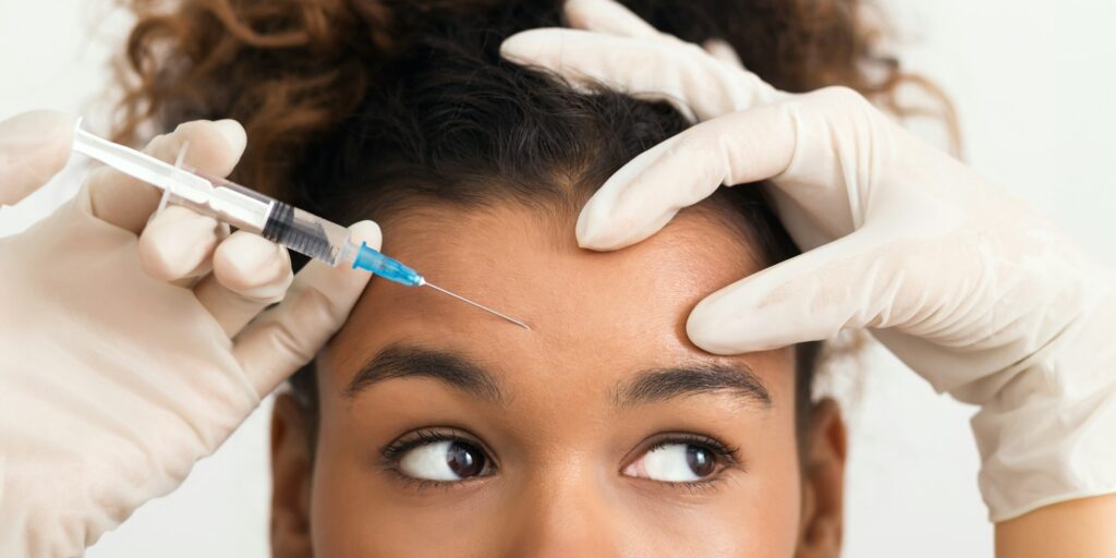 African-american woman getting botox injection in forehead