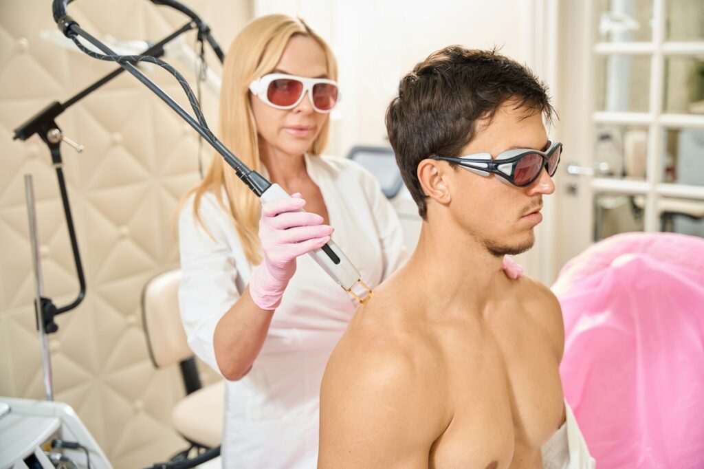 Female in protective glasses conducts a laser hair removal session