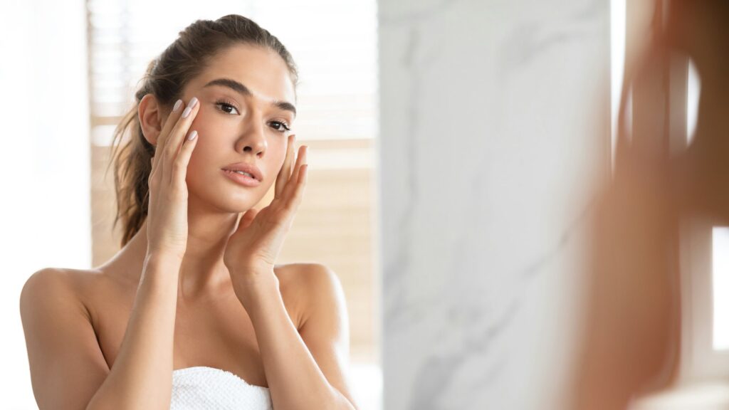 Young Woman Touching Face With Perfect Smooth Skin In Bathroom